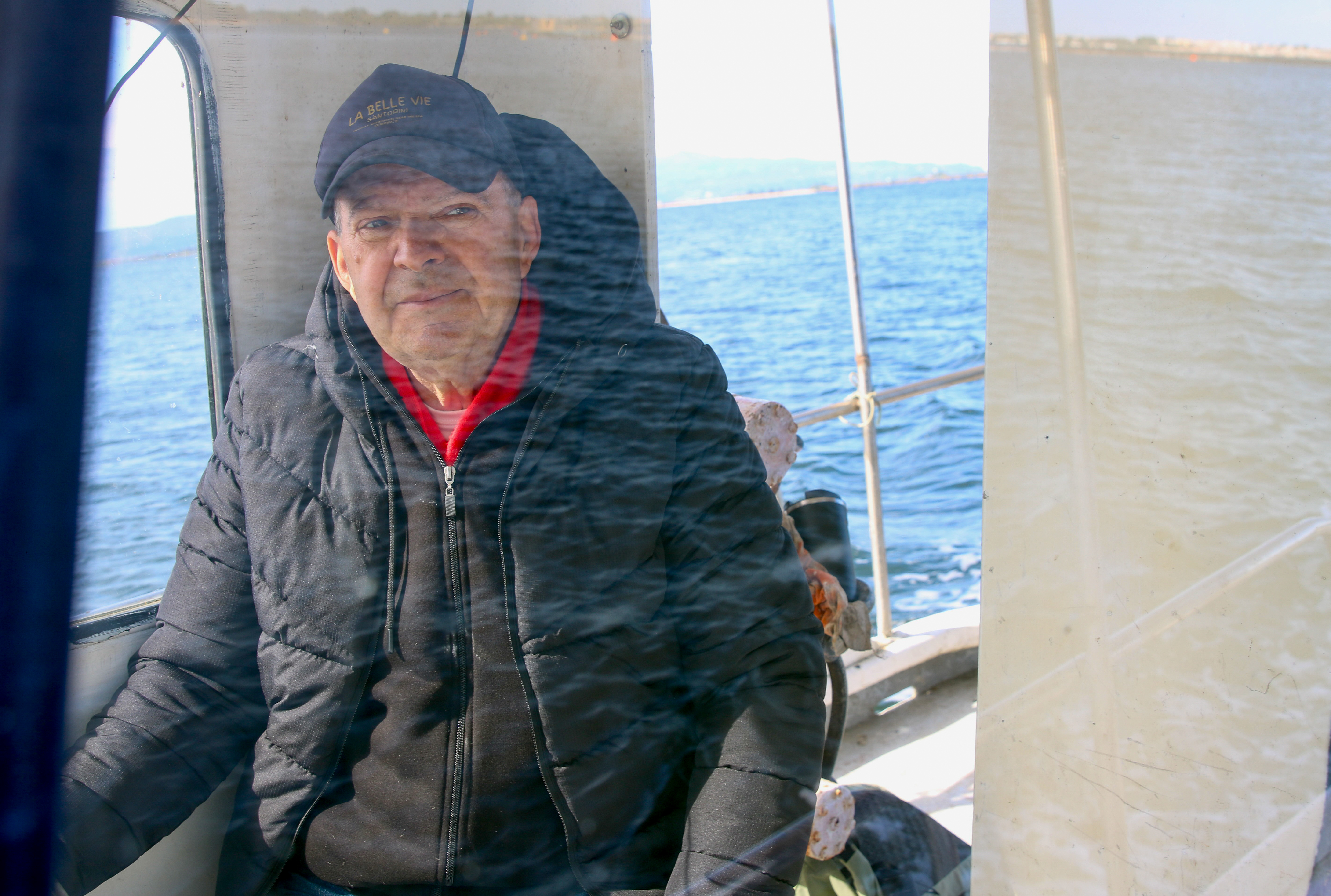 A fisher at the helm navigates past aquaculture infrastructure near Preveza, Greece. Over one third of farms have been left abandoned in the Ambracian Gulf.