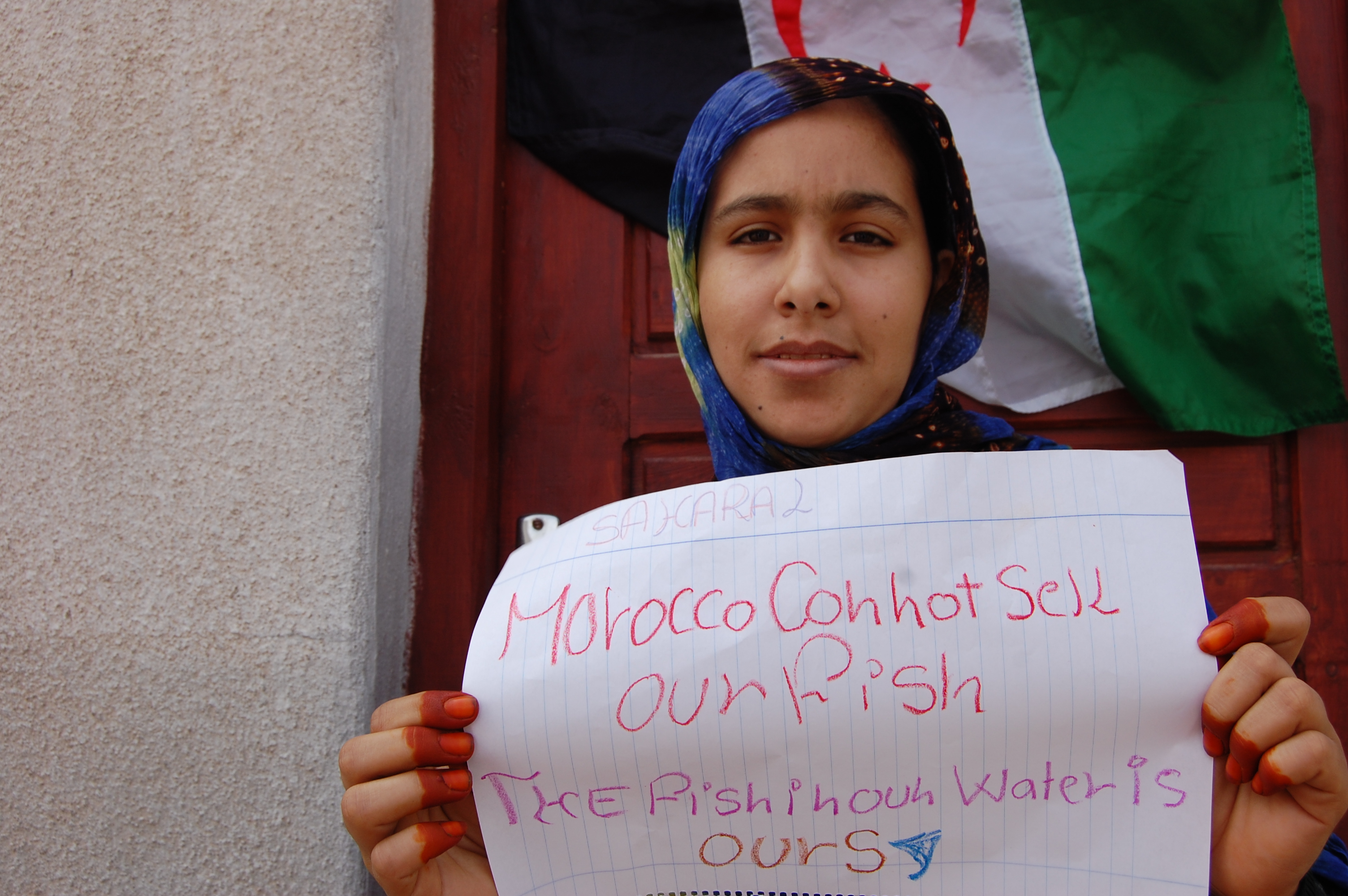 A Sahrawi girl held up a handwritten sign reading, “Morocco cannot sell our fish, the fish in our water is ours.”